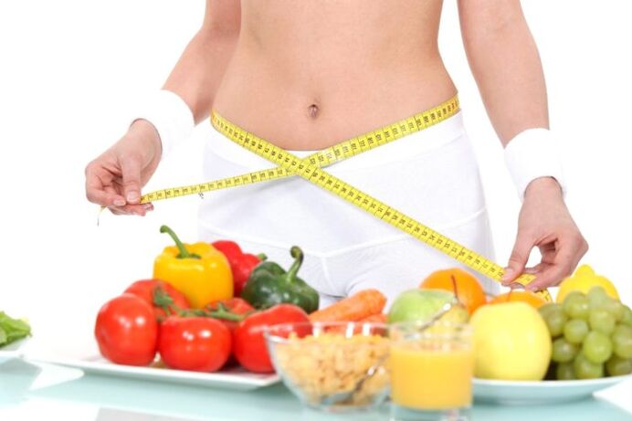 Girl measuring waist on groceries background